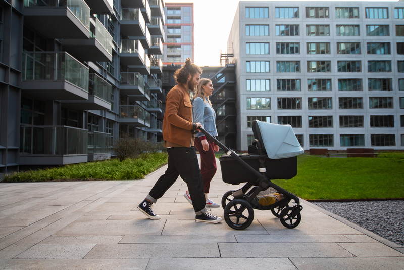 Eine junge Familie geht mit ihrem Baby in einem Kinderwagen spazieren