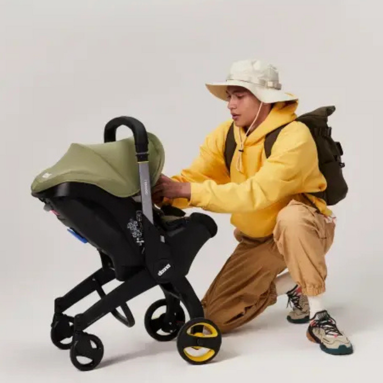 Mann mit gelben Pullover schaut in Babyschale 