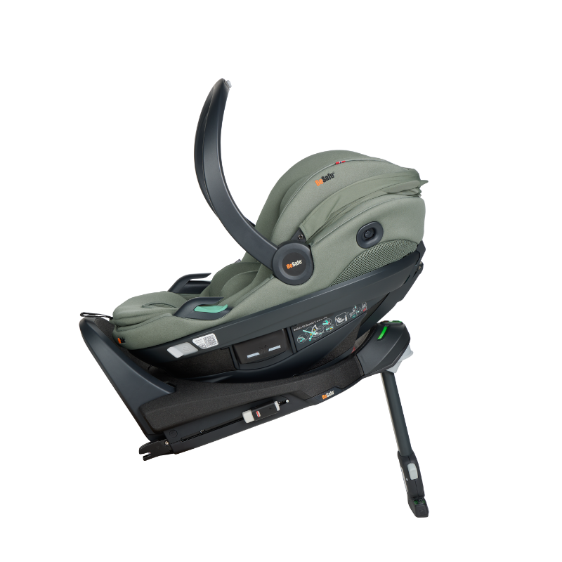 Grüne Babyschale mit Tragegriff, gepolsterter Liegefläche und integriertem Gurtsystem in schräger Seitenansicht auf einer Isofixstation fixiert.