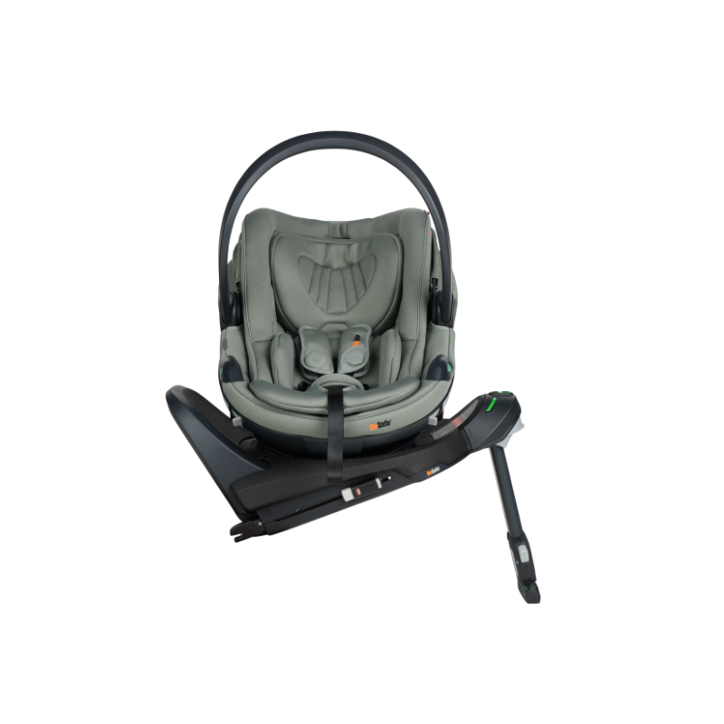 Grüne Babyschale mit Tragegriff, gepolsterter Liegefläche und integriertem Gurtsystem in schräger Seitenansicht, fixiert auf einer Isofixstation 90 Grad gedreht.