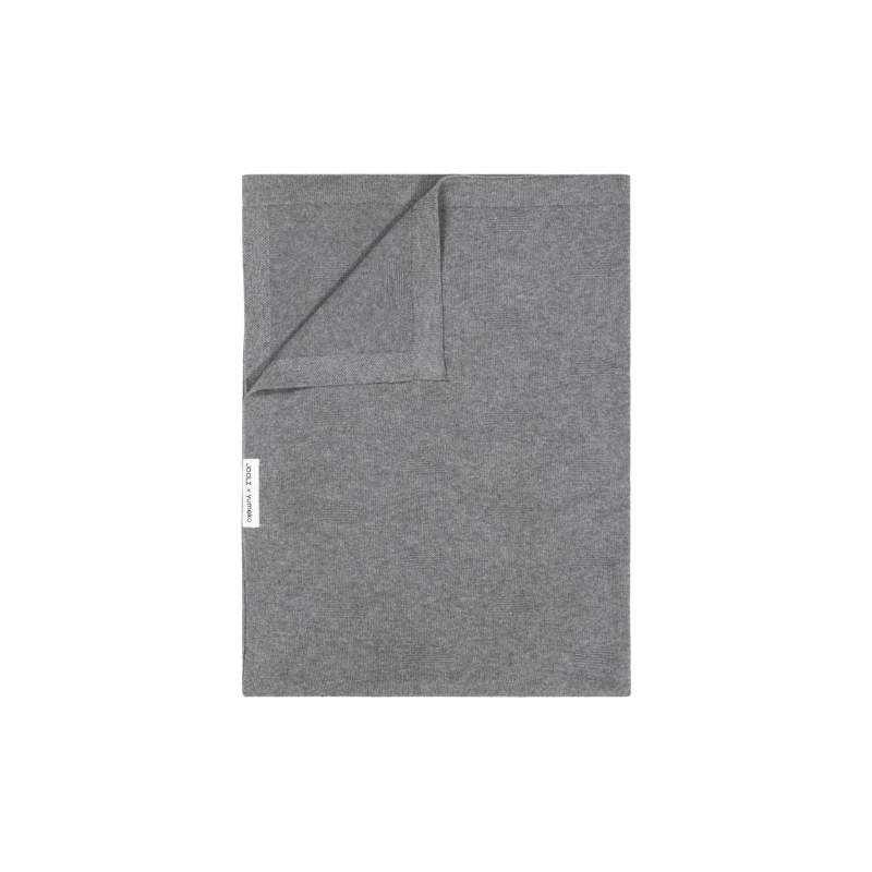 echteckige Decke aus Stoff in Graue Farbe, eine Ecke leicht umgeschlagen, mit kleinem seitlichem Etikett.