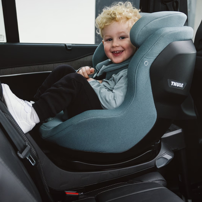 Thule Kindersitz im Auto – lachendes Kleinkind sitzt sicher in einem rückwärtsgerichteten Thule Reboarder mit gepolsterter Kopfstütze und ergonomischem Design